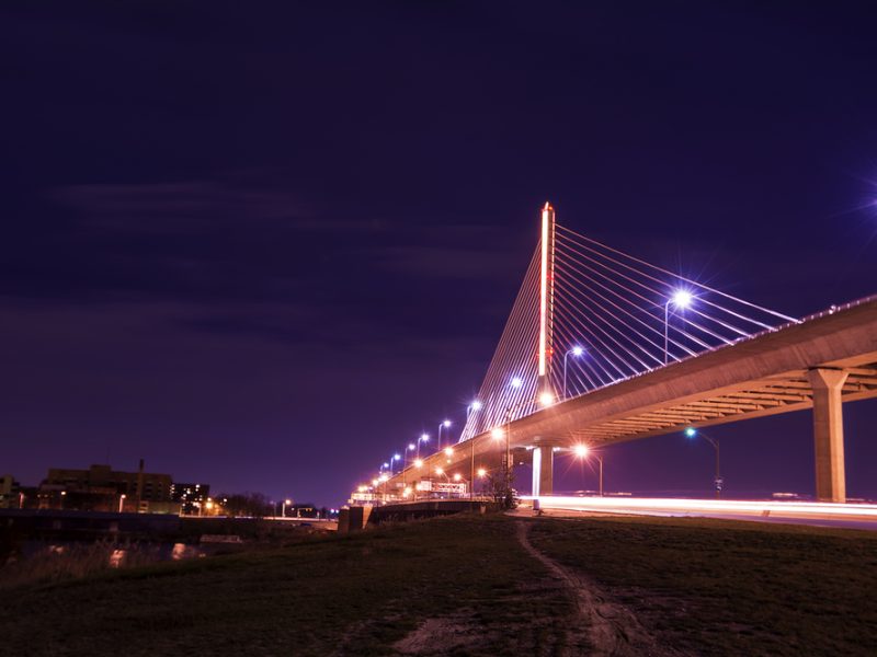 Night view of the Veterans' Glass City Skyway bridge in Toledo Ohio.  The bridges center pylon is lit up with LED lighting and the stainless steel cables are lit with floodlights.